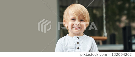 Blonde caucasian young boy smiling outdoors in white shirt with long hair 132094202