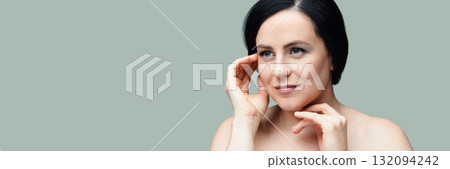 Caucasian mature woman with black hair posing against soft green background 132094242