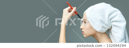 Young caucasian female applying makeup with brush wearing towel on head side Young caucasian female applying makeup with brush wearing towel on head side 132094294