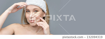 Caucasian female applying under-eye patches for skincare routine on grey Caucasian female applying under-eye patches for skincare routine on grey 132094319