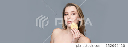 Young caucasian female holding skincare sponge against gray background 132094410