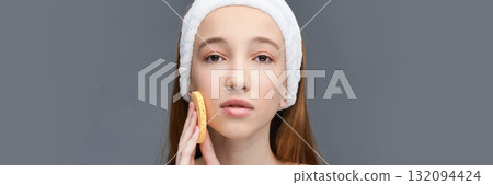 Young caucasian female using facial sponge on clear skin with headband on gray Young caucasian female using facial sponge on clear skin with headband on gray 132094424