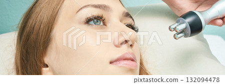 Young caucasian female receiving facial treatment with microcurrent device 132094478