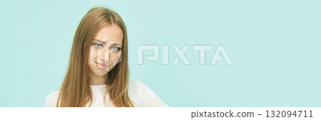 Young caucasian female with long hair smiling against light blue background Young caucasian female with long hair smiling against light blue background 132094711