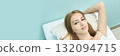 Young caucasian female relaxing on pillow against light turquoise background 132094715