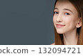 Smiling caucasian teen girl with long hair on dark gray background 132094721