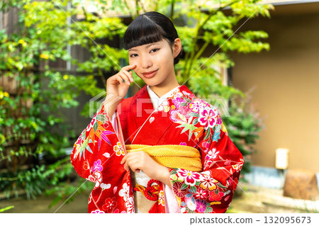 Japanese woman wearing a furisode kimono standing in the garden Japanese woman wearing a furisode kimono standing in the garden 132095673