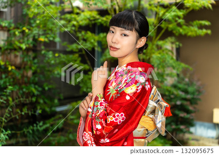 Japanese woman wearing a furisode kimono standing in the garden Japanese woman wearing a furisode kimono standing in the garden 132095675