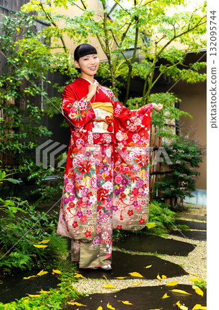 Japanese woman wearing a furisode kimono standing in the garden Japanese woman wearing a furisode kimono standing in the garden 132095744