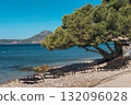 A bright, sunny, wide-angle photograph capturing a tranquil scene on a Mediterranean beach in a coastal resort area, likely in Montenegro or Croatia. 132096028