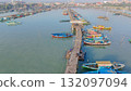Aerial view of a long wooden pier with colorful fishing boats in Gresik, East Java, showcasing coastal life. Aerial view of a long wooden pier with colorful fishing boats in Gresik, East Java, showcasing coastal life. 132097094