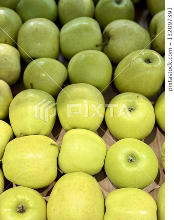 A vibrant and colorful display of fresh, crisp green apples organized neatly in a bustling market settings. Close-up. A vibrant and colorful display of fresh, crisp green apples organized neatly in a bustling market settings. Close-up. 132097391