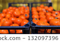 A vibrant display of ripe cherry tomatoes stacked neatly in a black basket at a bustling local market. Close-up. 132097396