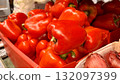 Vibrant red bell peppers are abundant in a market basket, showcasing their freshness and vivid color. Close-up. 132097399