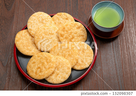 黑色背景中的醬油米餅和綠茶 132098307