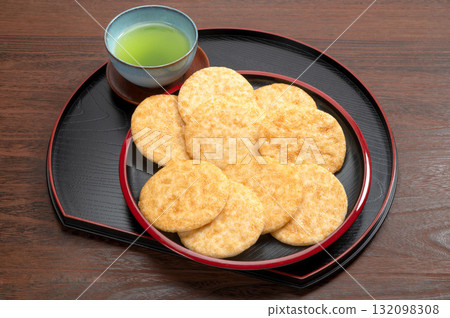 黑色背景中的醬油米餅和綠茶 132098308