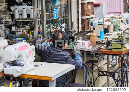 A man working with sewing machines and tools outside a shop in Busan, South Korea A man working with sewing machines and tools outside a shop in Busan, South Korea 132098395