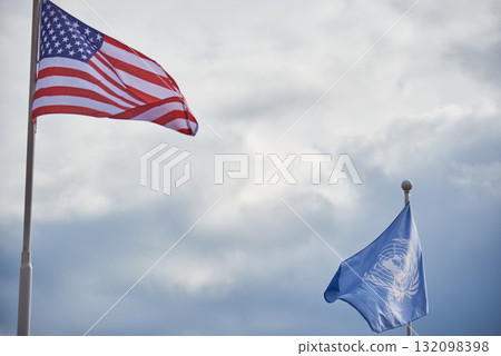 American and UN Flags Against Cloudy Sky 132098398