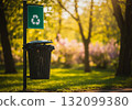 A garbage can in a park with a recycling symbol 132099380