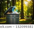 A metal trash can in a park with a graphic recycling symbol 132099381