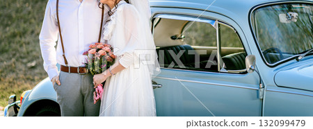 Young loving couple holding hands each other with wedding bouquet flowers , Bride and groom standing together in soft light of sunset 132099479