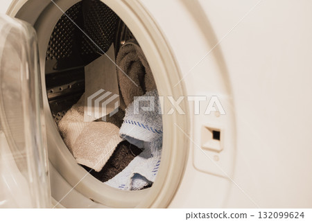White dye-catcher sheet lying in a washing machine drum with mixed laundry before wash 132099624