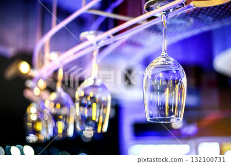 Empty wine glasses hanging up side down above a bar rack in night club Empty wine glasses hanging up side down above a bar rack in night club 132100731