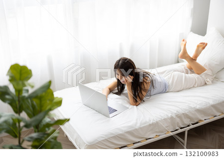 A young woman operating a computer in bed A young woman operating a computer in bed 132100983