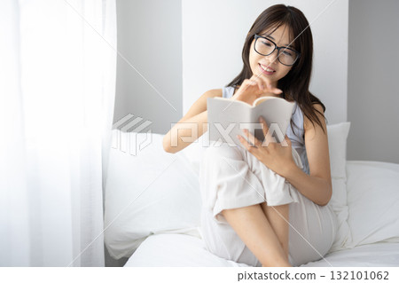 Young woman wearing glasses reading in bed Young woman wearing glasses reading in bed 132101062