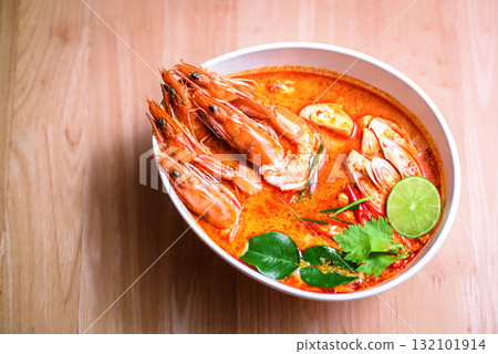 Thai hot spicy soup shrimp in coconut milk or Tom Yum Goong on wooden table Thai hot spicy soup shrimp in coconut milk or Tom Yum Goong on wooden table 132101914