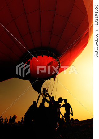 silhouette of people drag hot air balloon with basket at sunset silhouette of people drag hot air balloon with basket at sunset 132101950