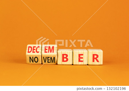 Symbol for the change from November to December. Businessman turns wooden cubes and changes the word November to December. Beautiful orange background. Happy December concept. Copy space. 132102196