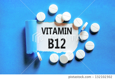 Vitamin B12 symbol. Concept words Vitamin B12 on beautiful white paper. White pills tablets. Beautiful blue background. Medical healthy lifestyle Vitamin B12 concept. Vitamin B12 symbol. Concept words Vitamin B12 on beautiful white paper. White pills tablets. Beautiful blue background. Medical healthy lifestyle Vitamin B12 concept. 132102302