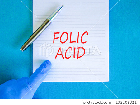 Folic acid symbol. Concept words Folic acid on beautiful white note. Doctor's hand in blue medical glove. Black pen. Beautiful blue background. Medical healthy lifestyle folic acid concept. 132102321