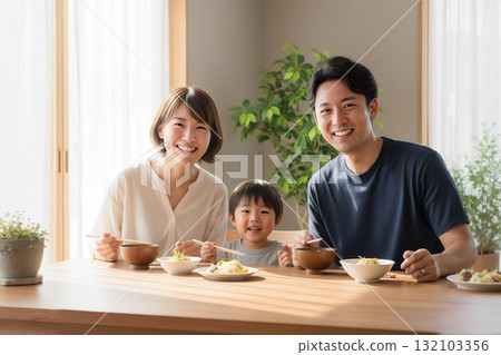 一家三口在明亮的餐廳裡微笑地享用美食 132103356