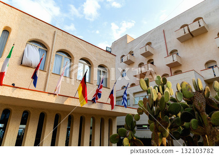 Mediterranean hotel facade with flags and cactuses Mediterranean hotel facade with flags and cactuses 132103782