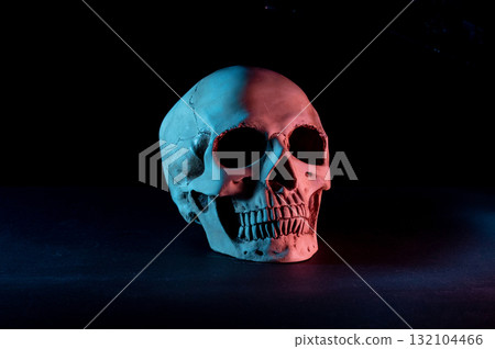 Human skull on a black background. Colored illumination of the skull. Skull turned to the side. 132104466