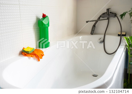 Close-up bottle of detergent is in bathroom of house with sponge cleaner and and rubber gloves on bath. Restoring order, cleanliness and hygiene in home, cleaning servise 132104714