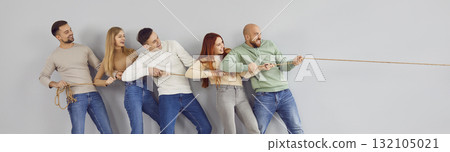 Group of happy smiling friends playing tug of war on grey color banner background 132105021