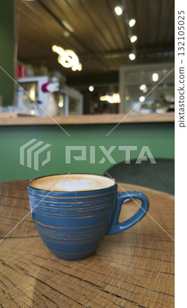 A cup of coffee with milk or cappuccino on a wooden table against the background of a modern cafe A cup of coffee with milk or cappuccino on a wooden table against the background of a modern cafe 132105025