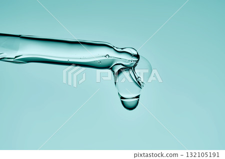 A drop of serum drips from a pipette on a delicate green background. 132105191