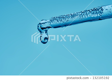 The texture of a cosmetic product with peptides in a pipette on a blue background. The texture of a cosmetic product with peptides in a pipette on a blue background. 132105192