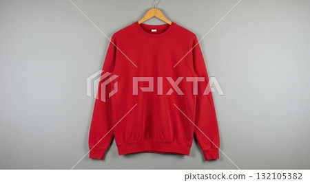 Red sweatshirt hanging on wooden hanger against gray background 132105382