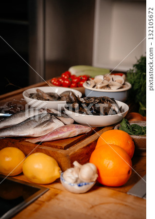 Sea bream, garlic, shrimp and shells on the table next to vegetables and fruit. Sea bream, garlic, shrimp and shells on the table next to vegetables and fruit. 132105672