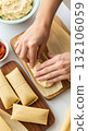 Making traditional tamales: hands close-up with corn husks and masa dough Making traditional tamales: hands close-up with corn husks and masa dough 132106059