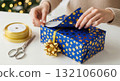 Wrapping a festive gift with blue and gold star paper for the holiday season Wrapping a festive gift with blue and gold star paper for the holiday season 132106060