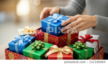 Hands arranging colorful wrapped gifts with ribbons for holiday celebrations 132106064