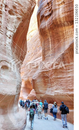 A group of tourists walks through the narrow canyon A group of tourists walks through the narrow canyon 132106650