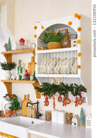 Kitchen shelves decorated with festive garlands, Christmas tree and ornaments for winter holidays Kitchen shelves decorated with festive garlands, Christmas tree and ornaments for winter holidays 132106950