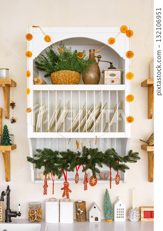 Kitchen shelves decorated with festive garlands, Christmas tree and ornaments for winter holidays 132106951